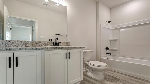 bathroom featuring wood finished floors, toilet, vanity, and shower / tub combination