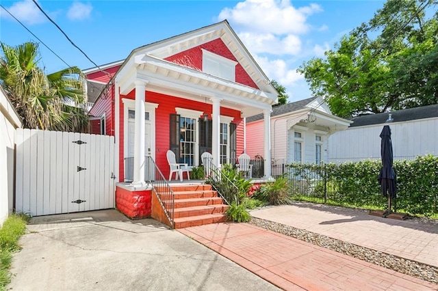 view of front of home with a porch, a gate, and fence