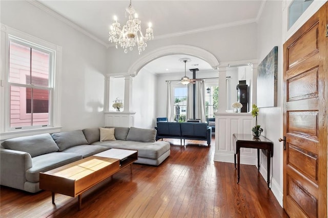 living room with decorative columns, hardwood / wood-style floors, crown molding, arched walkways, and a chandelier
