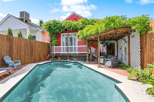 view of swimming pool featuring a wooden deck, a fenced backyard, cooling unit, and a pergola