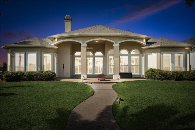 2283 Sunset Blvd, Slidell, LA 70461 - rear view of house featuring a yard, stucco siding, a chimney, and a shingled roof