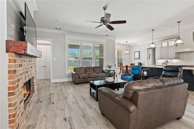 2021 Cypress Bend Dr, Madisonville, LA 70447 - living area featuring a ceiling fan, light wood-style floors, a brick fireplace, crown molding, and baseboards