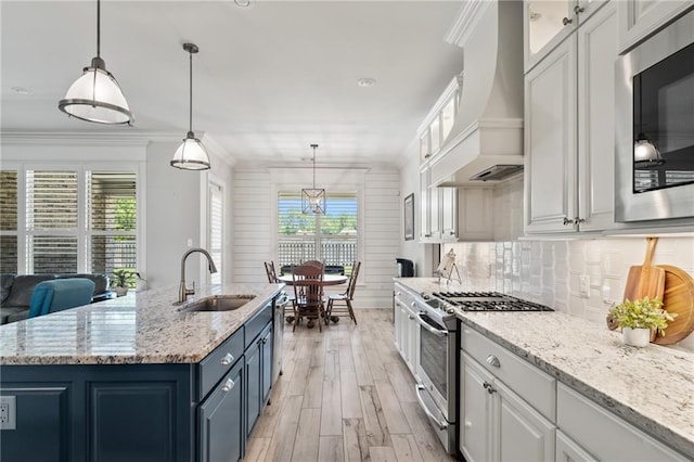 2021 Cypress Bend Dr, Madisonville, LA 70447 - kitchen with stainless steel appliances, a sink, blue cabinetry, premium range hood, and white cabinetry