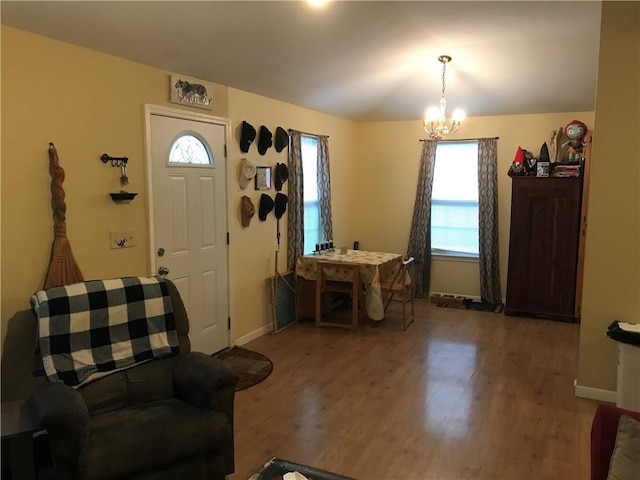 foyer with healthy amount of natural light, wood finished floors, and a chandelier