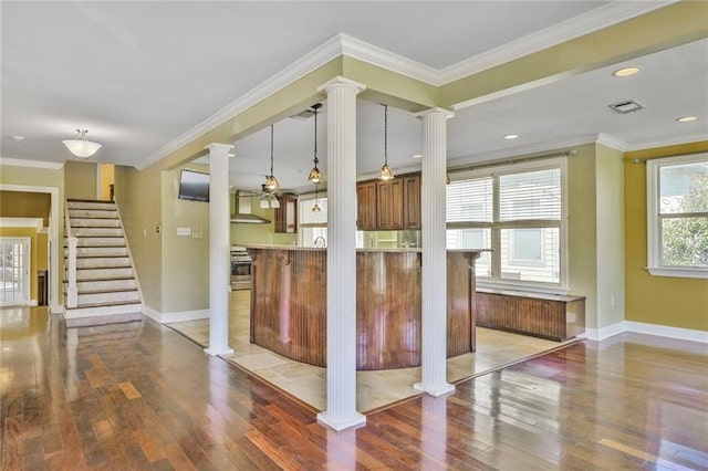 3630 Octavia St, New Orleans, LA 70125 - kitchen featuring ornate columns, wood-type flooring, wall chimney exhaust hood, baseboards, and hanging light fixtures