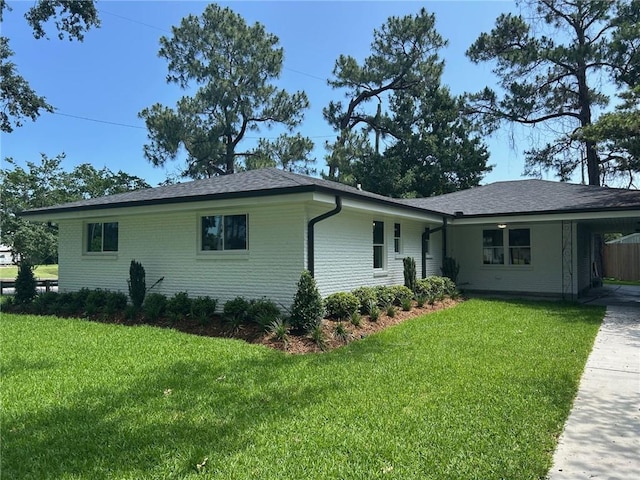 view of front of house with a front yard, a carport, and roof with shingles