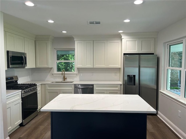 kitchen with stainless steel appliances, a sink, dark wood finished floors, a kitchen island, and white cabinets