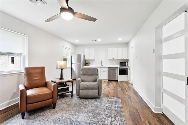 living area featuring baseboards, wood finished floors, ceiling fan, and recessed lighting