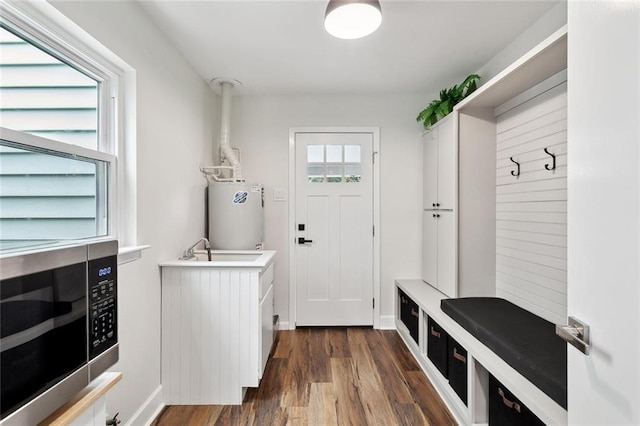 mudroom featuring water heater, dark wood-type flooring, and a sink