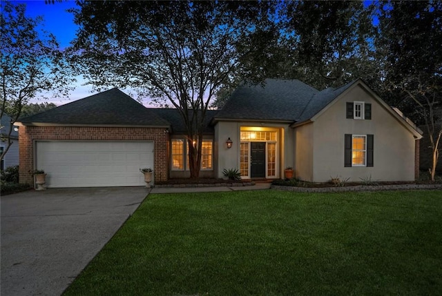 view of front of home with a garage, concrete driveway, a lawn, stucco siding, and a shingled roof
