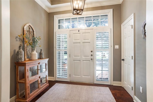 foyer entrance with ornamental molding, baseboards, dark wood-style flooring, and a chandelier