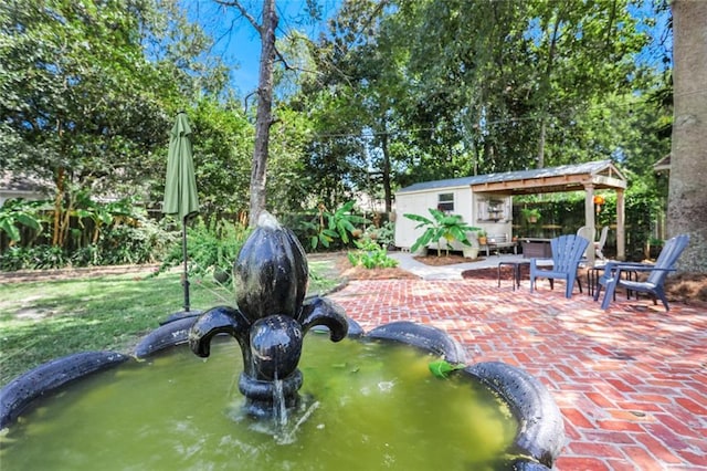 view of patio / terrace with an outdoor structure and a garden pond
