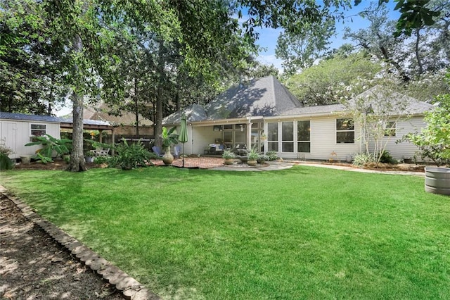 rear view of property featuring a yard, a patio, and roof with shingles