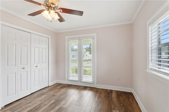 unfurnished bedroom with wood finished floors, baseboards, crown molding, a closet, and a ceiling fan