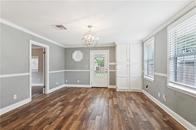 empty room with a chandelier, dark wood-style flooring, crown molding, and baseboards