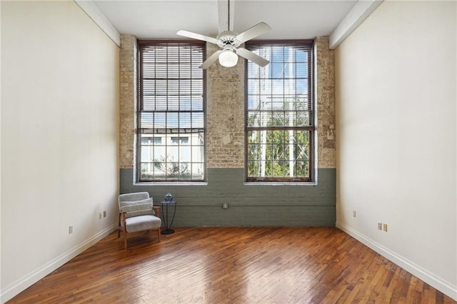 unfurnished room featuring healthy amount of natural light, hardwood / wood-style floors, and a ceiling fan