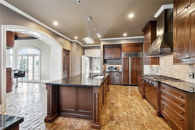 54 Beresford Dr, Metairie, LA 70001 - kitchen featuring wall chimney range hood, a sink, appliances with stainless steel finishes, dark stone countertops, and backsplash
