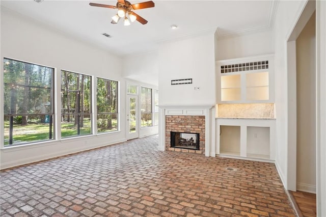 125 Secluded Forest Way, Madisonville, LA 70447 - unfurnished living room featuring a ceiling fan, crown molding, brick patterned flooring, a brick fireplace, and baseboards