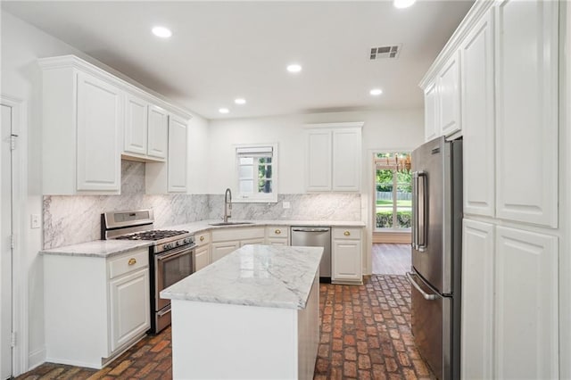 125 Secluded Forest Way, Madisonville, LA 70447 - kitchen featuring appliances with stainless steel finishes, a sink, brick flooring, white cabinets, and recessed lighting
