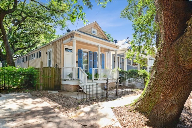 8216 Spruce St, New Orleans, LA 70118 - shotgun-style home featuring a porch and a fenced front yard