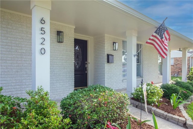 property entrance with brick siding and covered porch
