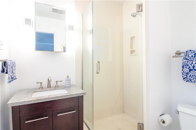 bathroom with a shower stall, toilet, and vanity