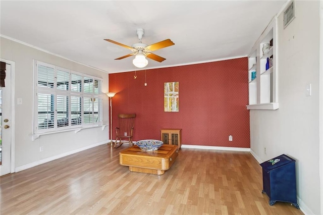 403 Athania Pkwy, Metairie, LA 70001 - living area featuring an accent wall, a ceiling fan, ornamental molding, wood finished floors, and baseboards