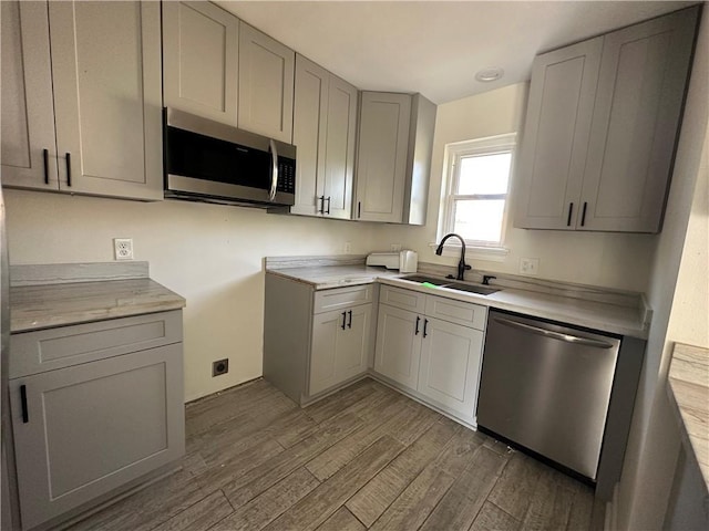 1561 Curtis St, Harvey, LA 70058 - kitchen featuring appliances with stainless steel finishes, a sink, wood finished floors, gray cabinetry, and light countertops