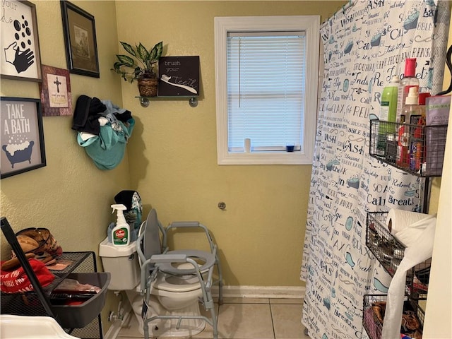 interior space with tile patterned floors, baseboards, a shower with shower curtain, and toilet