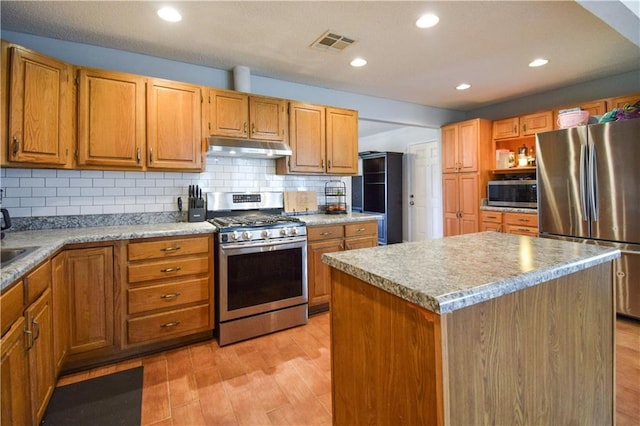 kitchen featuring appliances with stainless steel finishes, under cabinet range hood, tasteful backsplash, light wood-type flooring, and recessed lighting