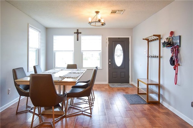 dining space featuring a chandelier, wood finished floors, a textured ceiling, and baseboards