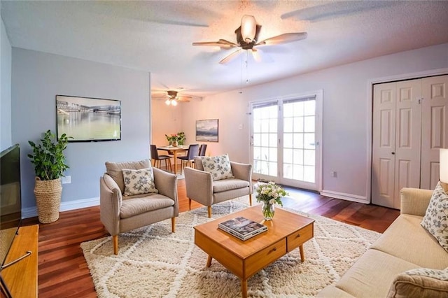 living area with a ceiling fan, baseboards, and wood finished floors