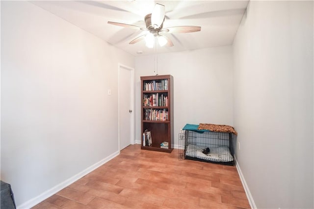 empty room with ceiling fan, light wood-style flooring, and baseboards