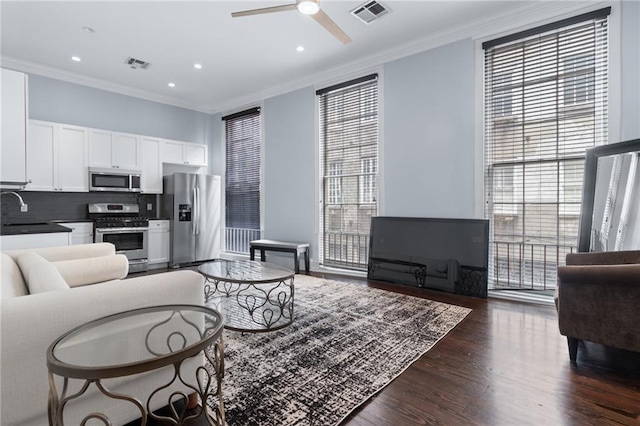 living room with ornamental molding, ceiling fan, dark wood finished floors, and recessed lighting