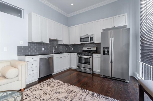 kitchen featuring stainless steel appliances, dark wood-style flooring, a sink, crown molding, and white cabinetry