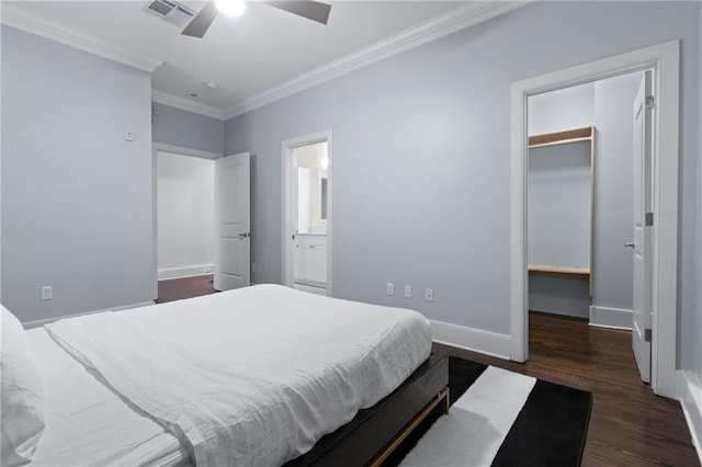 bedroom with ornamental molding, a spacious closet, dark wood finished floors, baseboards, and a closet