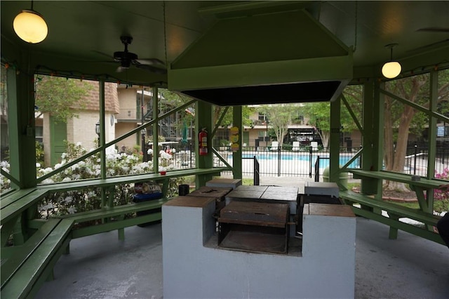view of patio with a ceiling fan, a community pool, fence, and stairs