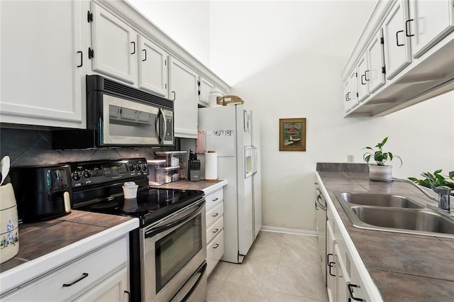 kitchen featuring stainless steel appliances, a sink, white cabinetry, backsplash, and baseboards