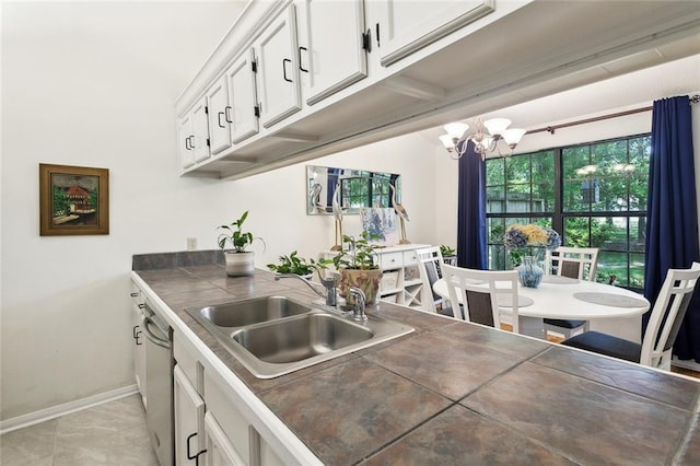 kitchen with white cabinetry, a chandelier, a sink, baseboards, and dishwasher