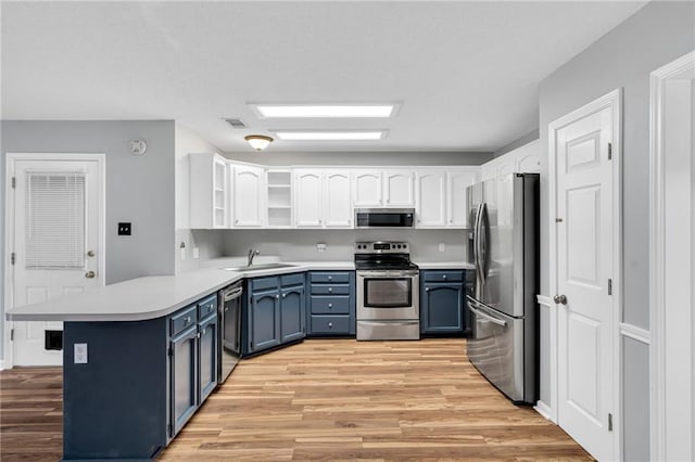 3737 James Victor Dr, Baton Rouge, LA 70817 - kitchen with stainless steel appliances, a peninsula, a sink, light wood-style floors, and white cabinets
