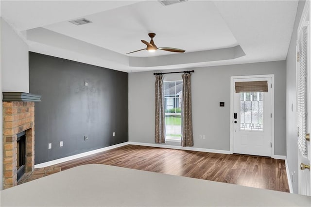 3737 James Victor Dr, Baton Rouge, LA 70817 - unfurnished living room featuring a tray ceiling, wood finished floors, ceiling fan, and healthy amount of natural light