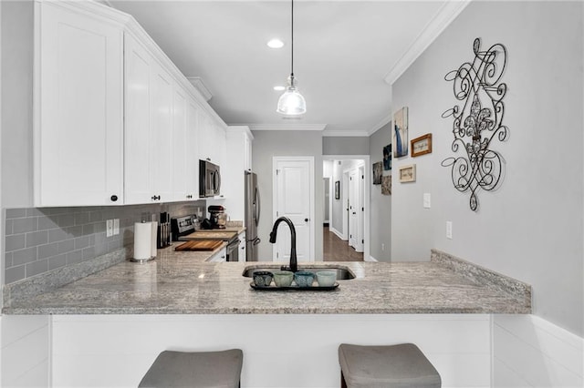 3986 Main St, Zachary, LA 70791 - kitchen featuring appliances with stainless steel finishes, a sink, a peninsula, decorative backsplash, and white cabinets