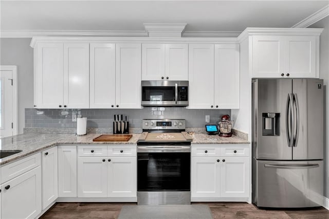 3986 Main St, Zachary, LA 70791 - kitchen featuring appliances with stainless steel finishes, crown molding, white cabinetry, light stone countertops, and decorative backsplash
