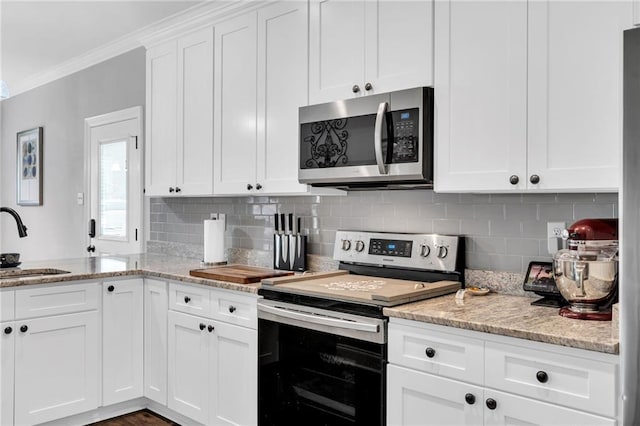 3986 Main St, Zachary, LA 70791 - kitchen with appliances with stainless steel finishes, a sink, ornamental molding, decorative backsplash, and white cabinetry