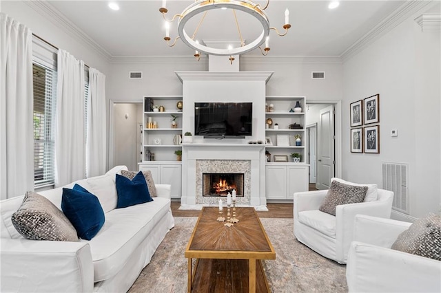 336 Rue St, Emilion, Covington, LA 70433 - living area with a chandelier, light wood-style floors, a warm lit fireplace, and ornamental molding