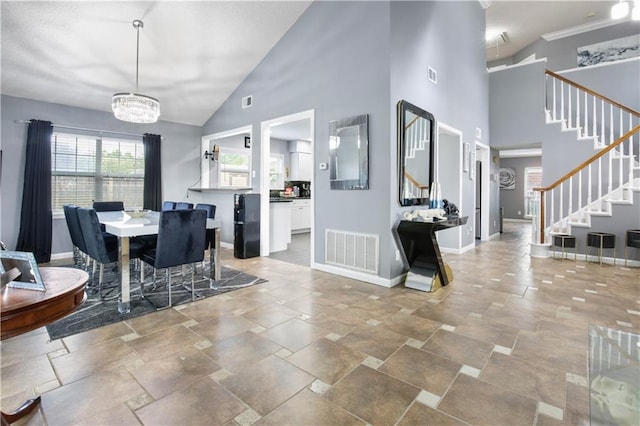 126 Silverwood Dr, Slidell, LA 70461 - dining room featuring stairway, a chandelier, baseboards, high vaulted ceiling, and stone tile flooring