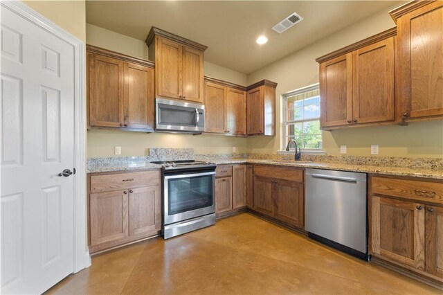 200 Cotton Ln, Hammond, LA 70401 - kitchen with stainless steel appliances, a sink, brown cabinets, light stone countertops, and recessed lighting