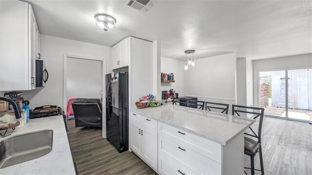 778 Heritage Ave, Gretna, LA 70056 - kitchen with black appliances, a sink, a kitchen bar, wood finished floors, and a peninsula