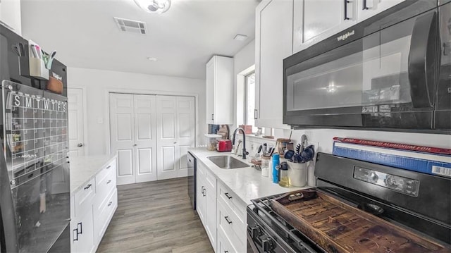 778 Heritage Ave, Gretna, LA 70056 - kitchen with stainless steel appliances, a sink, white cabinets, light stone counters, and wood finished floors