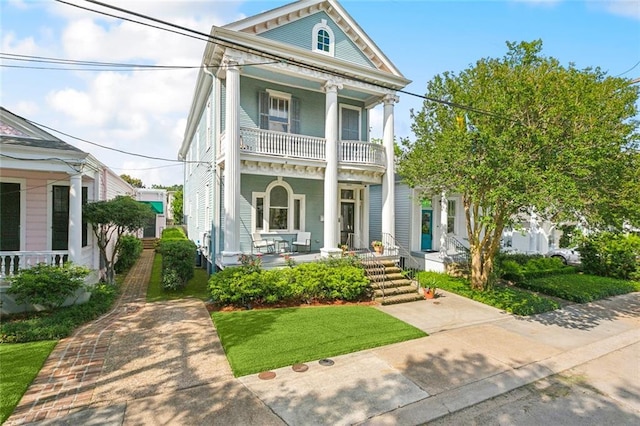 neoclassical home with covered porch, a balcony, and a front yard